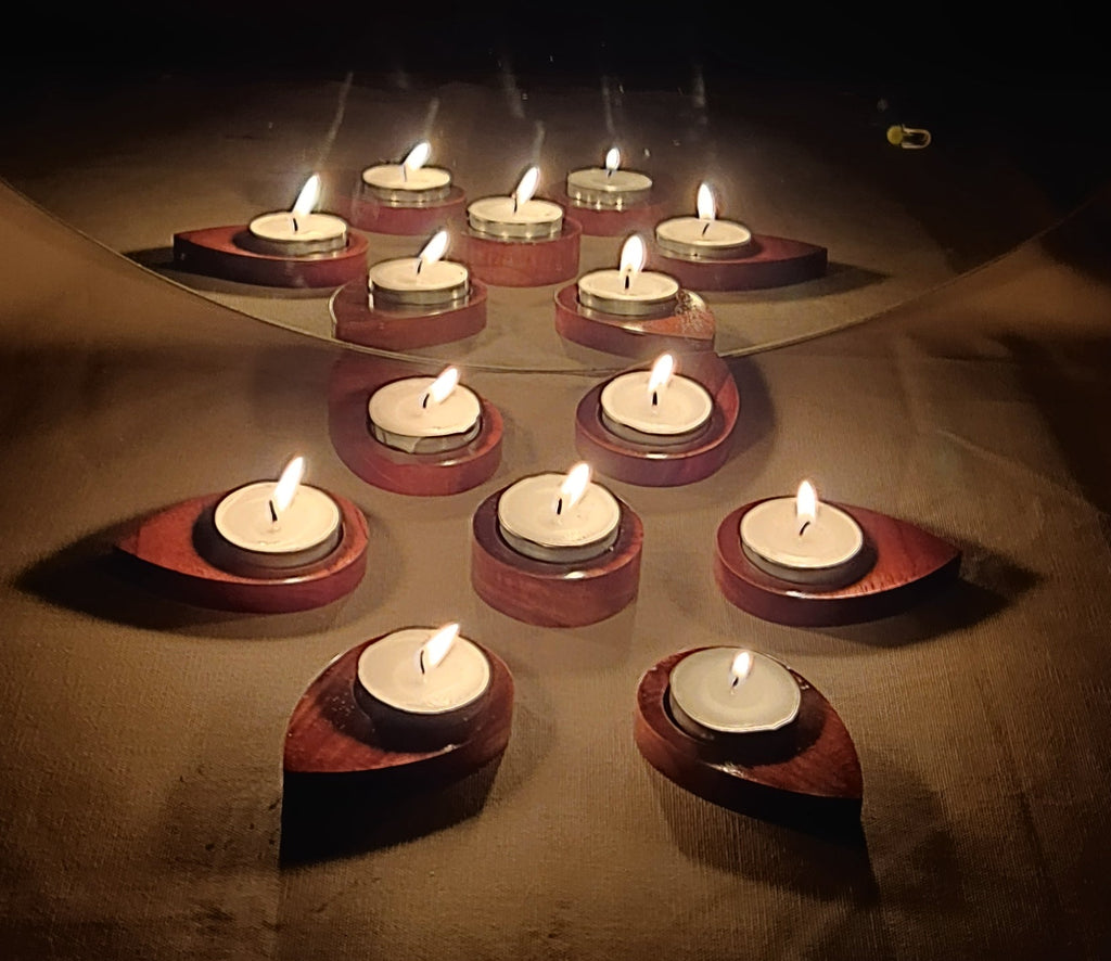 Pear-shaped wooden tea light holder glowing with candlelight on a styled table
