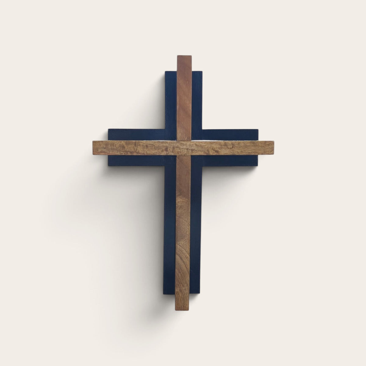 A modern wall cross with layered wooden cross elements in brown and beige tones, mounted on a light beige wall.